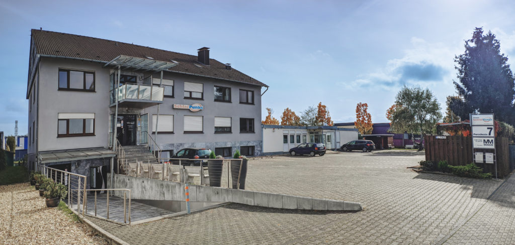 Front Ansicht zu Parkplatzeinfahrt von Hotel-Pension Schlafpunkt in Leverkusen bei Köln Nähe Düsseldorf.
Man erkennt die Fenster front der Zimmer und Apartments und Saalreingang